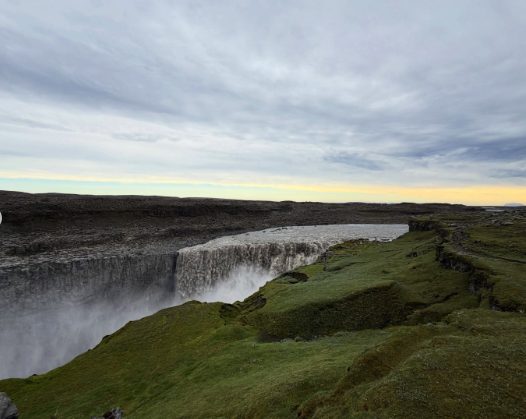 Dettifoss under a low arctic sun, with the mossy slope of the west rim in the foreground