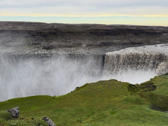 The wall of spray at Dettifoss rising above a rim of bright green moss